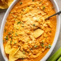 overhead view of vegan buffalo chicken dip in a large white baking dish surrounded by tortilla chips.