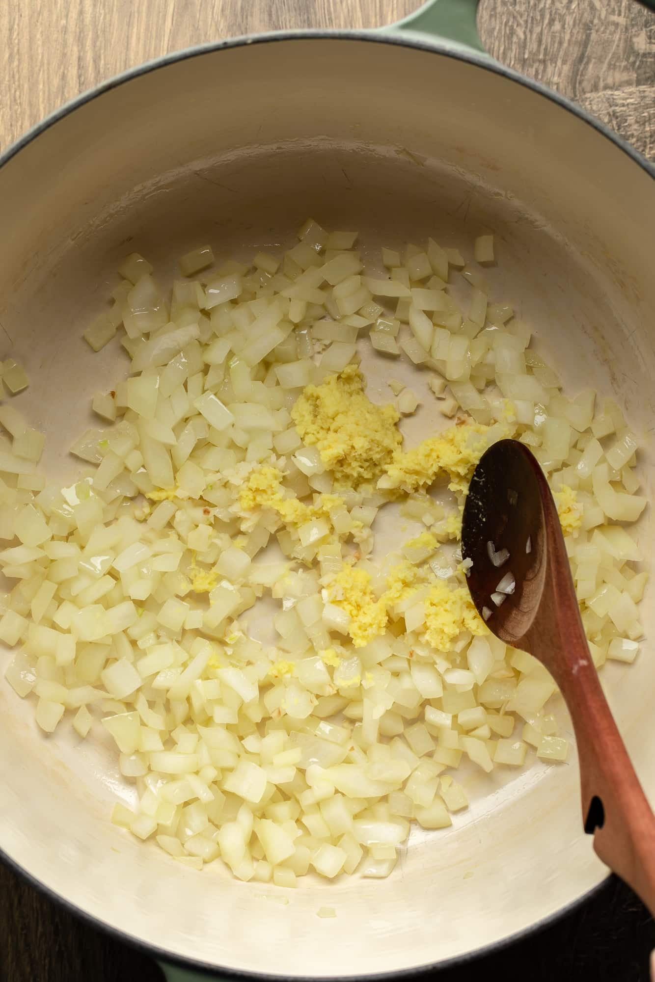 cooking chopped onions and ginger for carrot and ginger soup in a large pot.