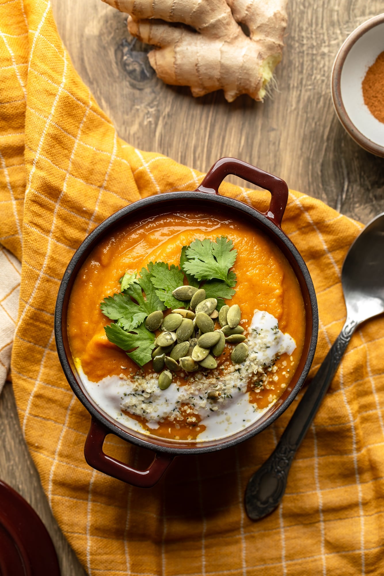 overhead view of a bowl of vegan carrot and ginger soup topped with cilantro and pepitas.