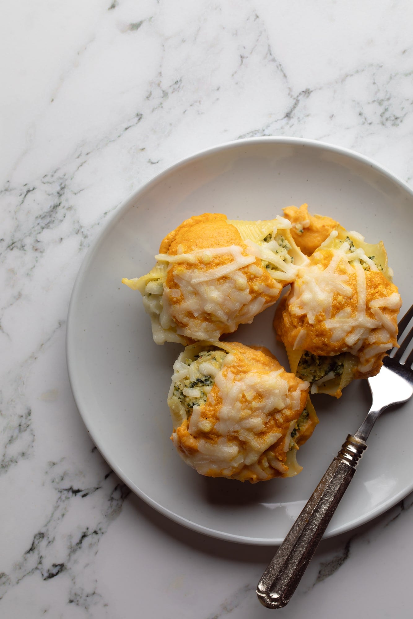 overhead view of 3 vegan pumpkin stuffed shells on a plate.
