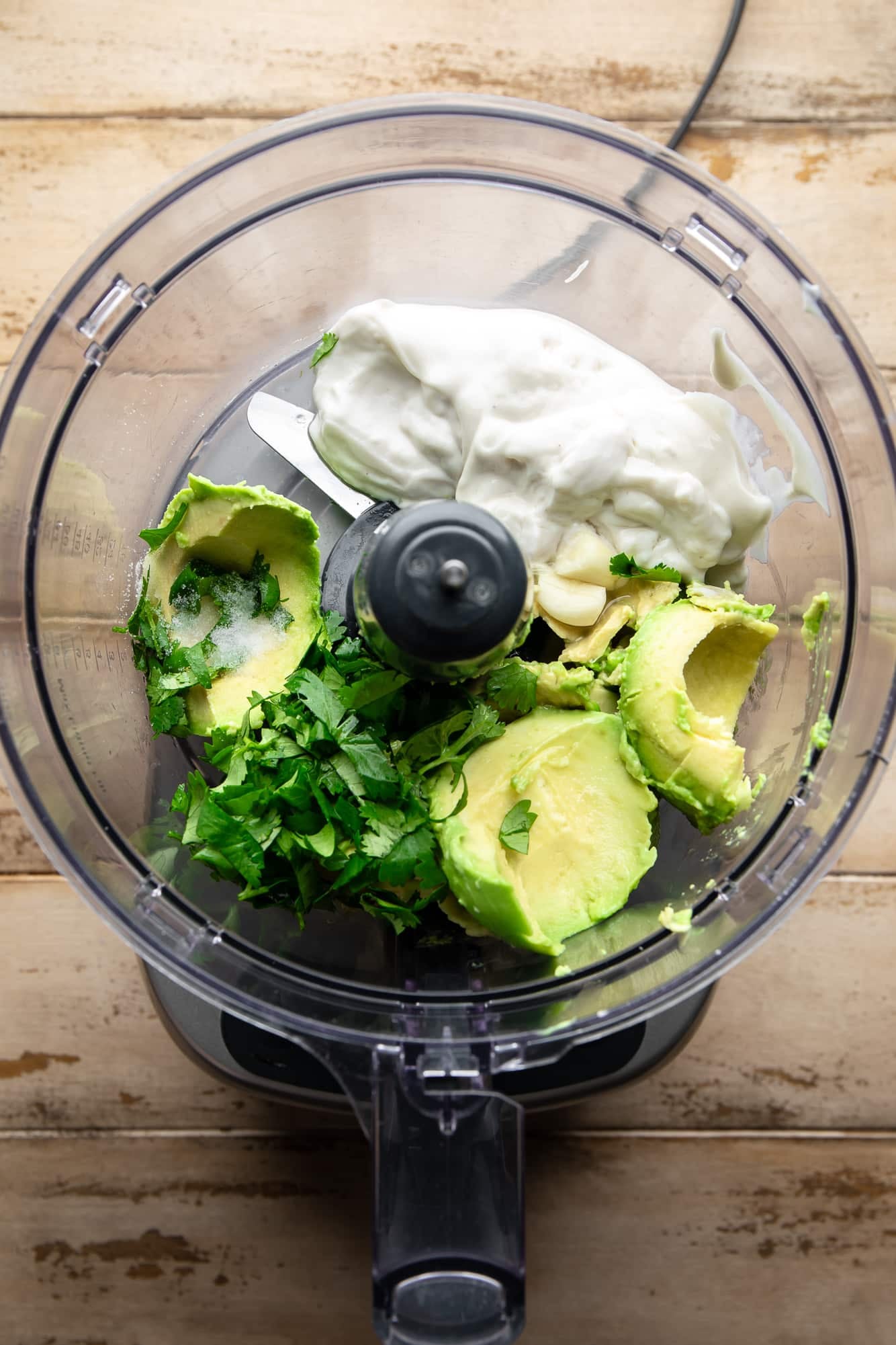 the ingredients for vegan avocado crema in a food processor.