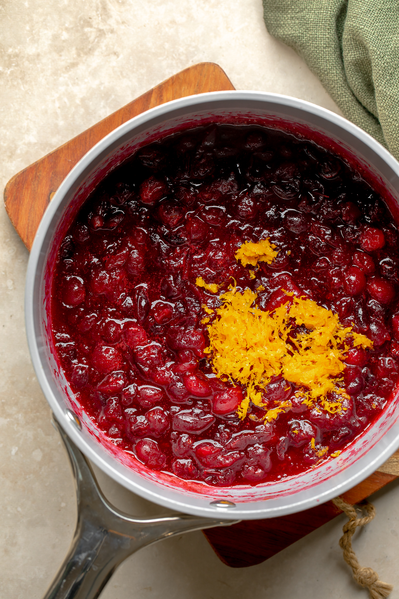 overhead view of orange cranberry sauce topped with orange zest in a saucepan.