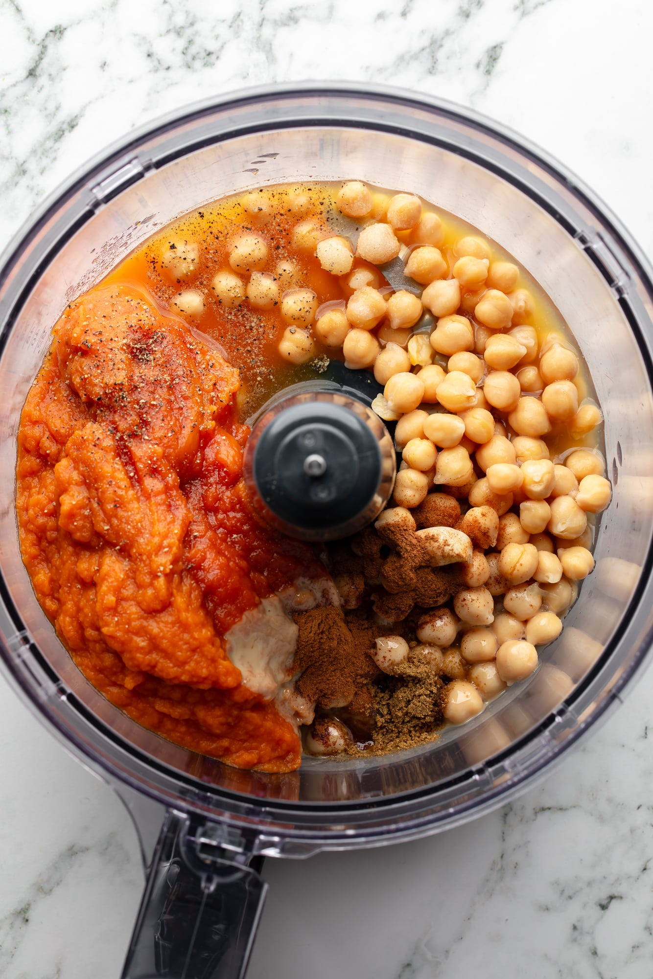 overhead view of the ingredients for pumpkin hummus in a food processor.