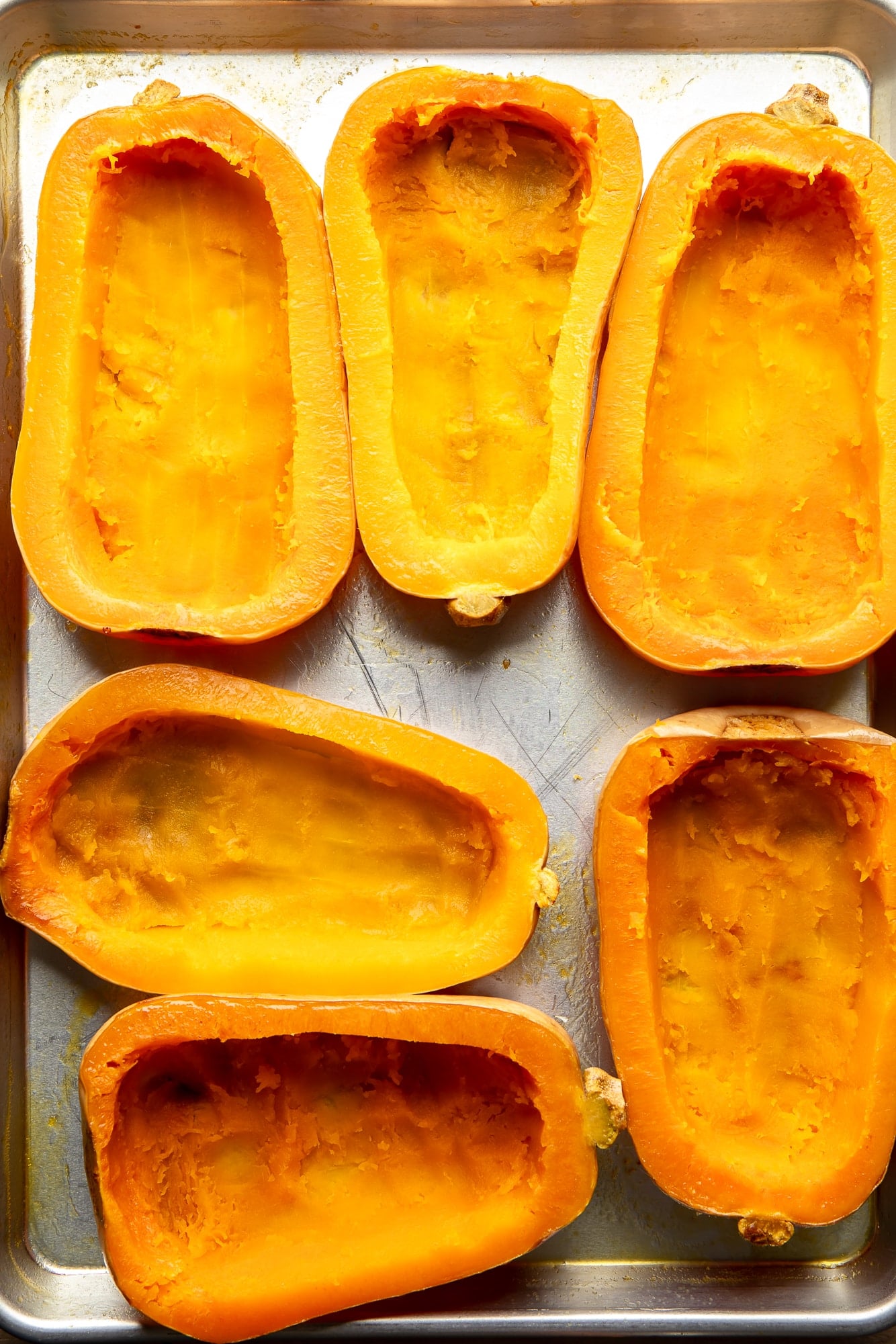 roasted and hollowed out butternut squashes on a baking sheet.