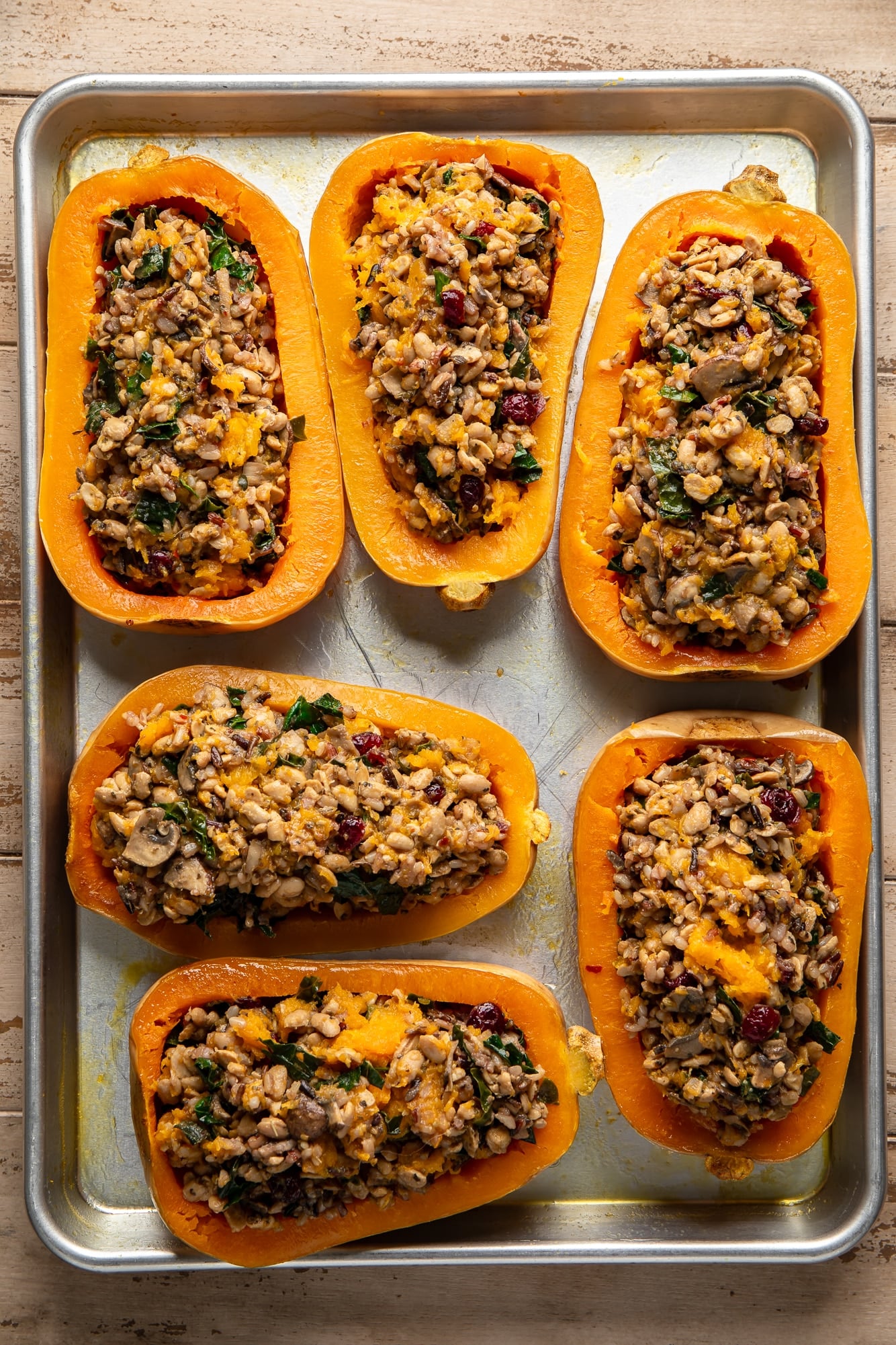 overhead view of stuffed butternut squashes on a baking sheet.