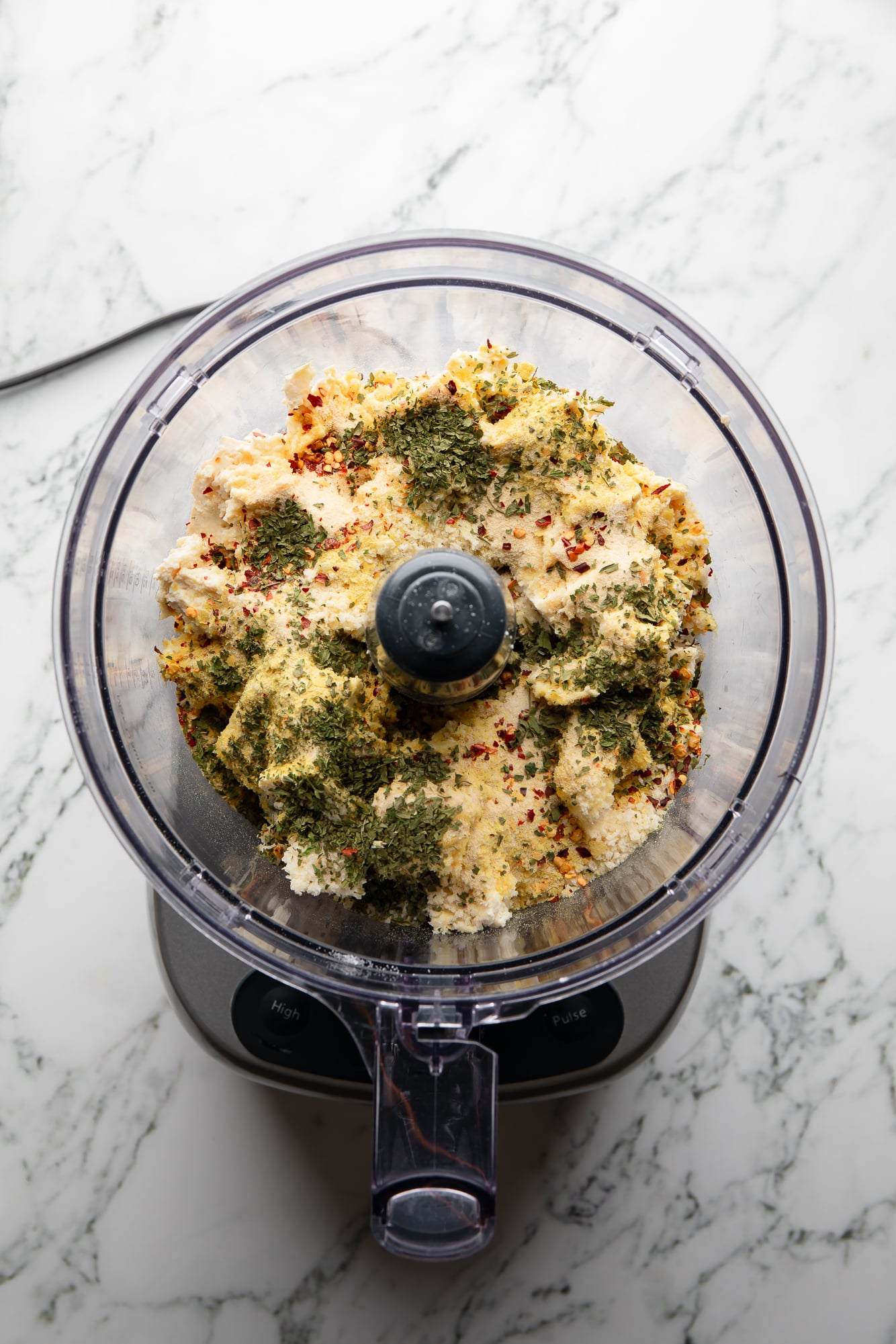overhead view of the ingredients for a tofu meatball mixture in a food processor.