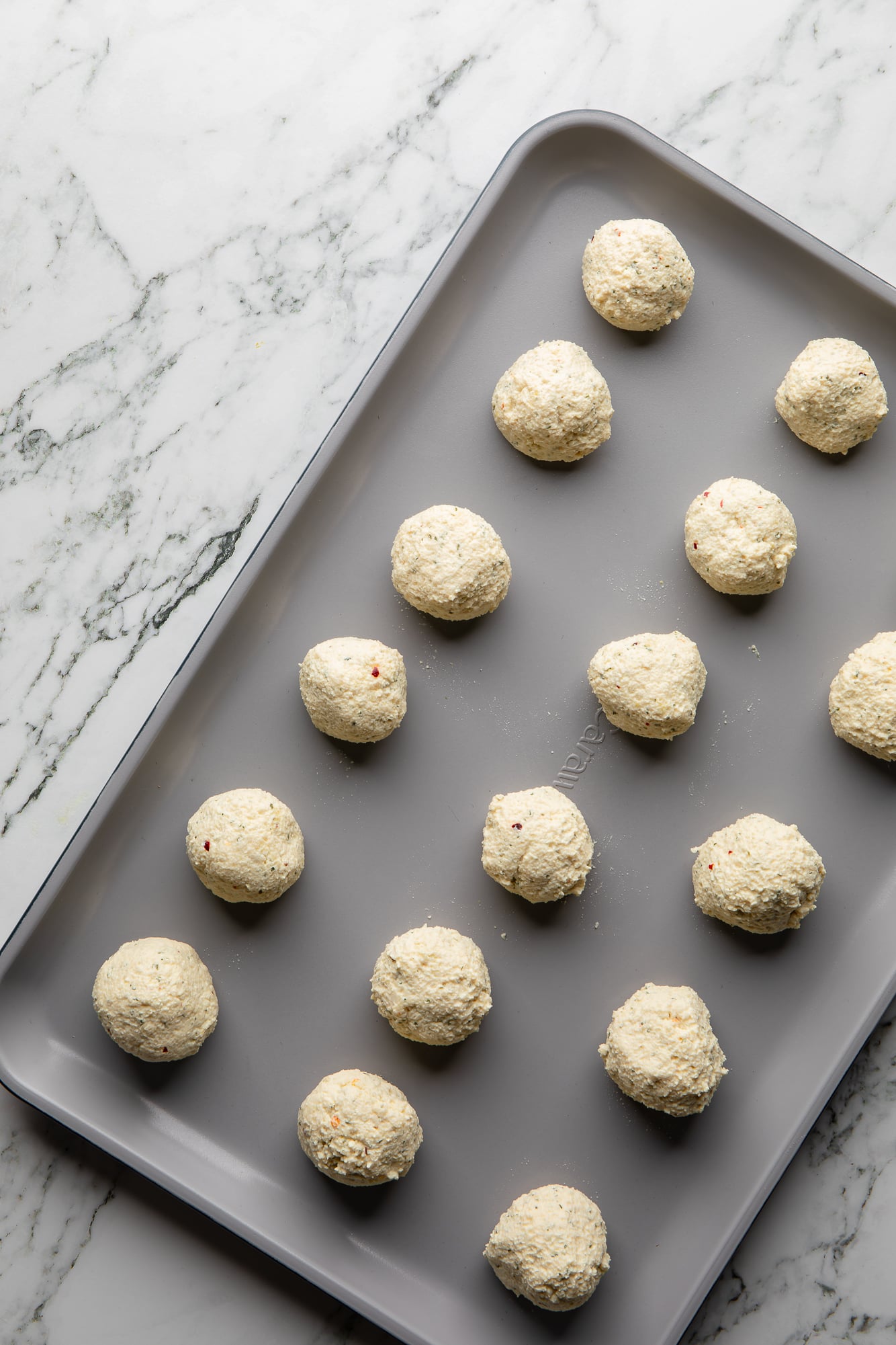 overhead view of unbaked tofu meatballs on a baking sheet.