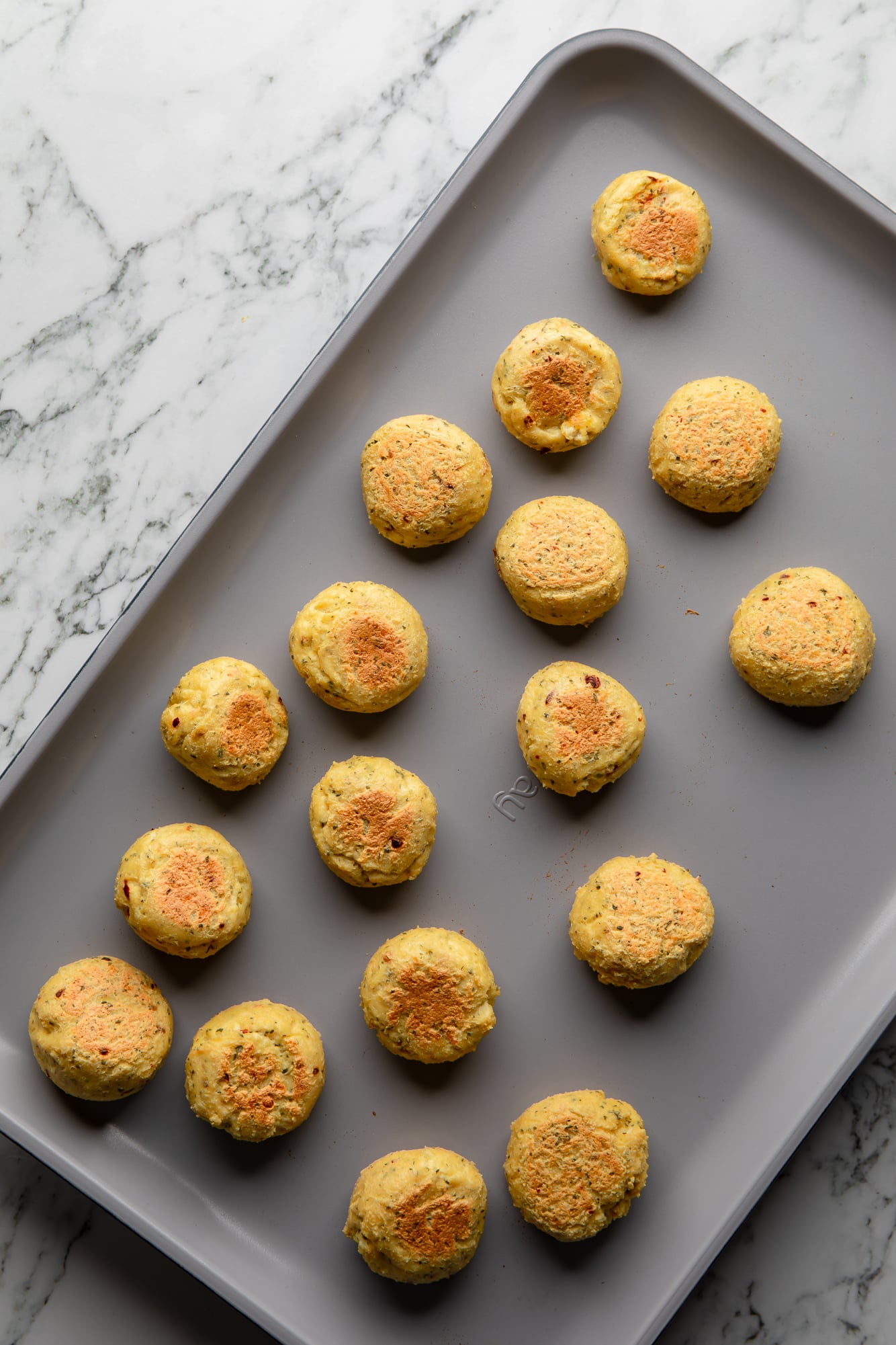 overhead view of baked tofu meatballs on a baking sheet.