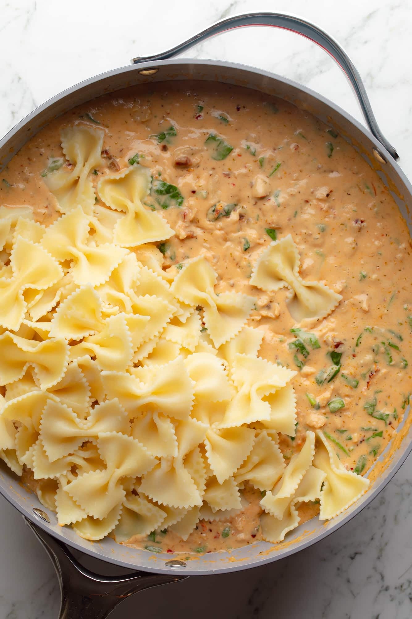 overhead view of cooked pasta in a vegan marry me pasta sauce in a large skillet.