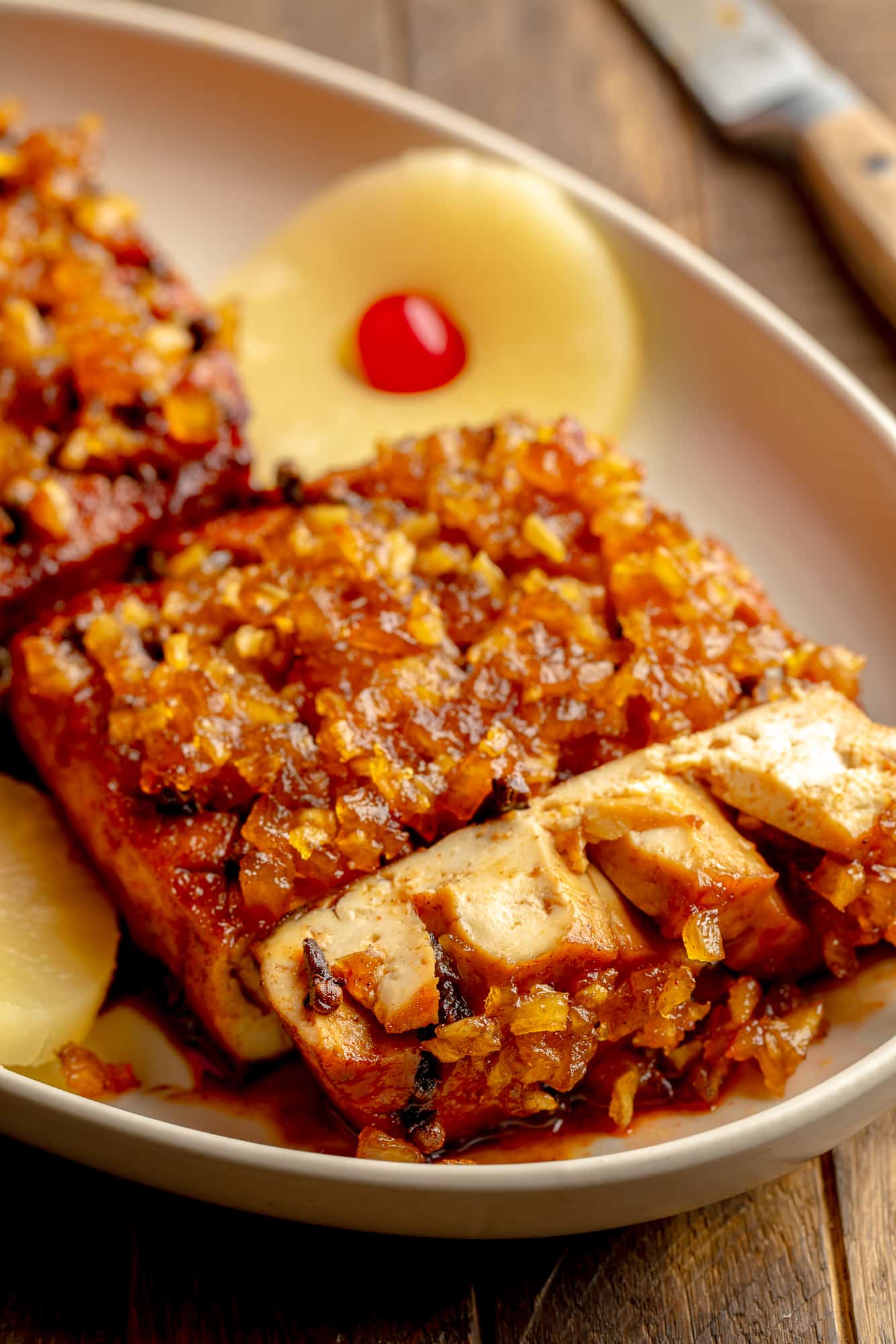 side view of a sliced pineapple glazed tofu roast in a serving dish.