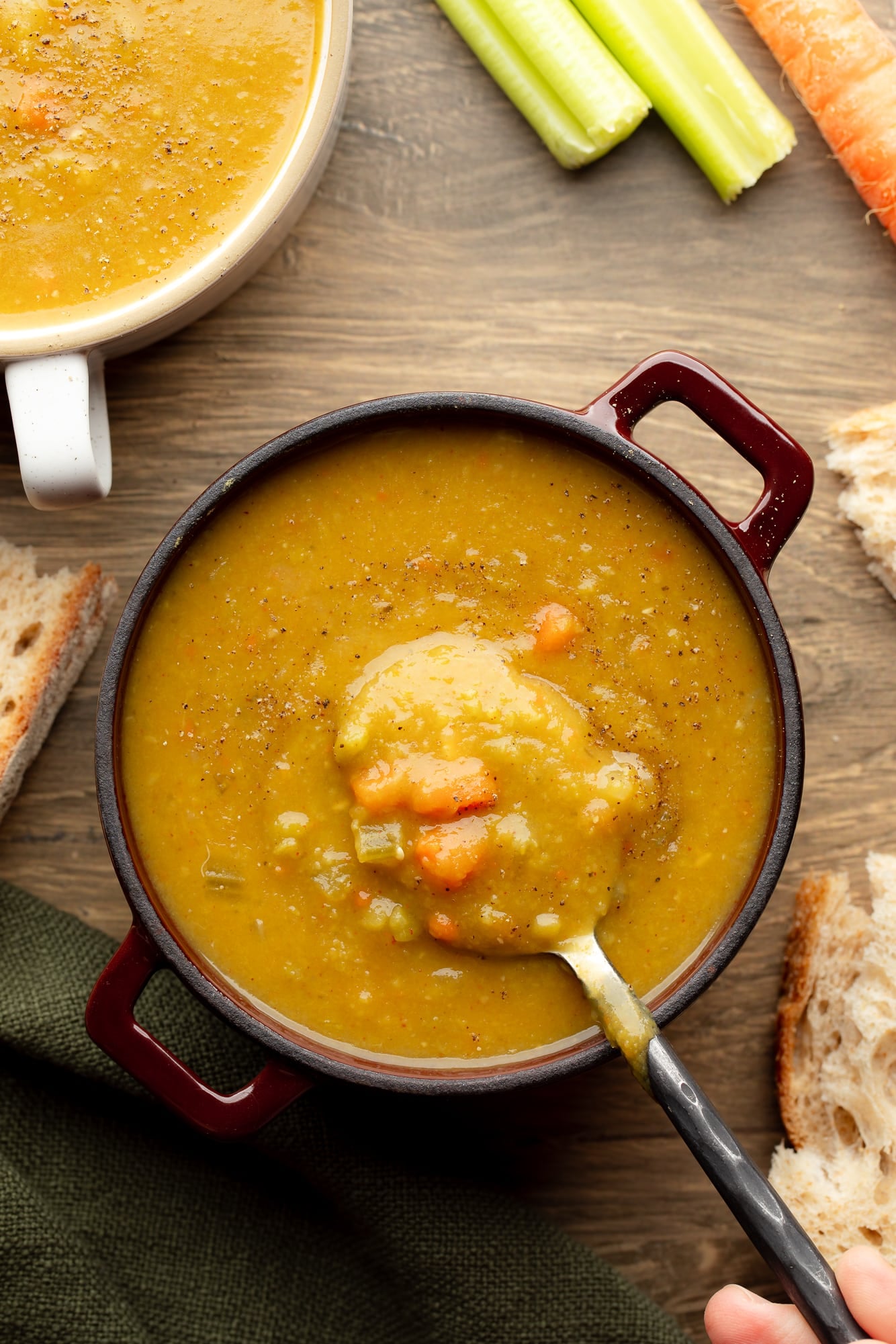 overhead view of a spoon being lifted out of a bowl of vegan split pea soup.