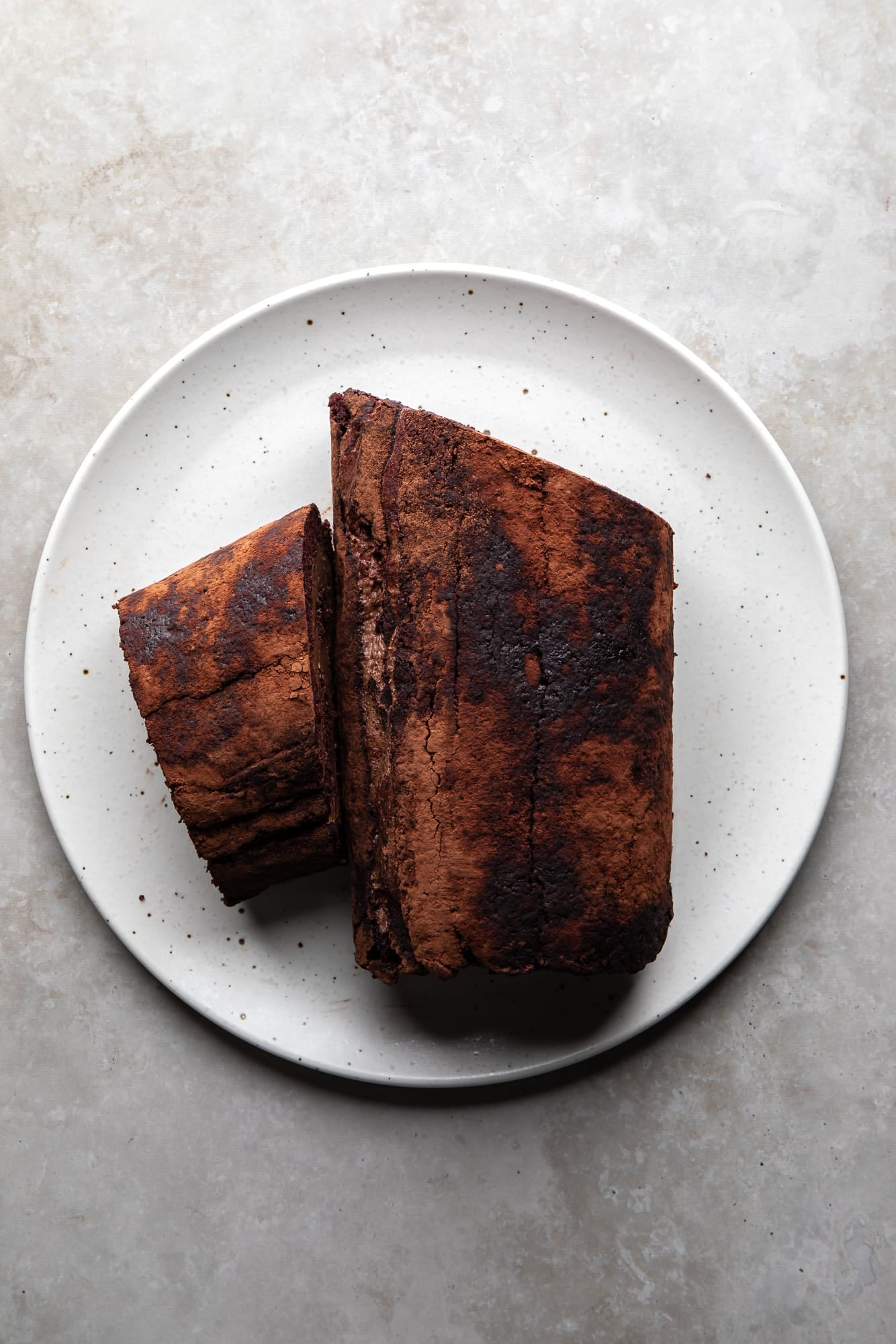 overhead view of an undecorated yule log cake on a white plate.