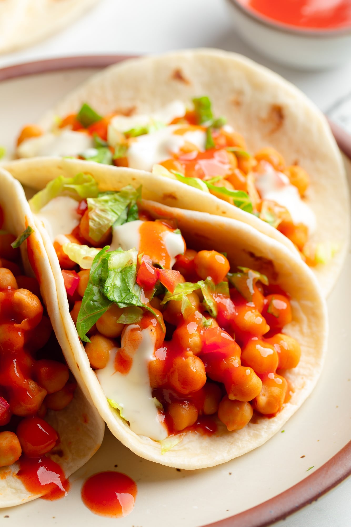 close up on 3 buffalo chickpea tacos on a plate.