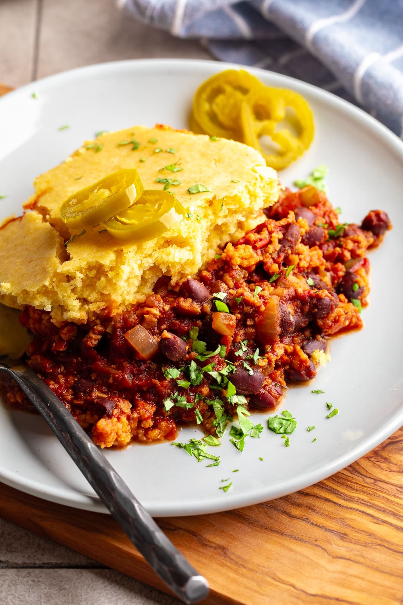 side view of a slice of chili cornbread casserole on a white plate.