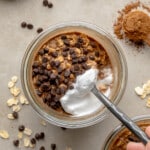 overhead view of a spoon scooping up a bite of chocolate overnight oats from a jar.