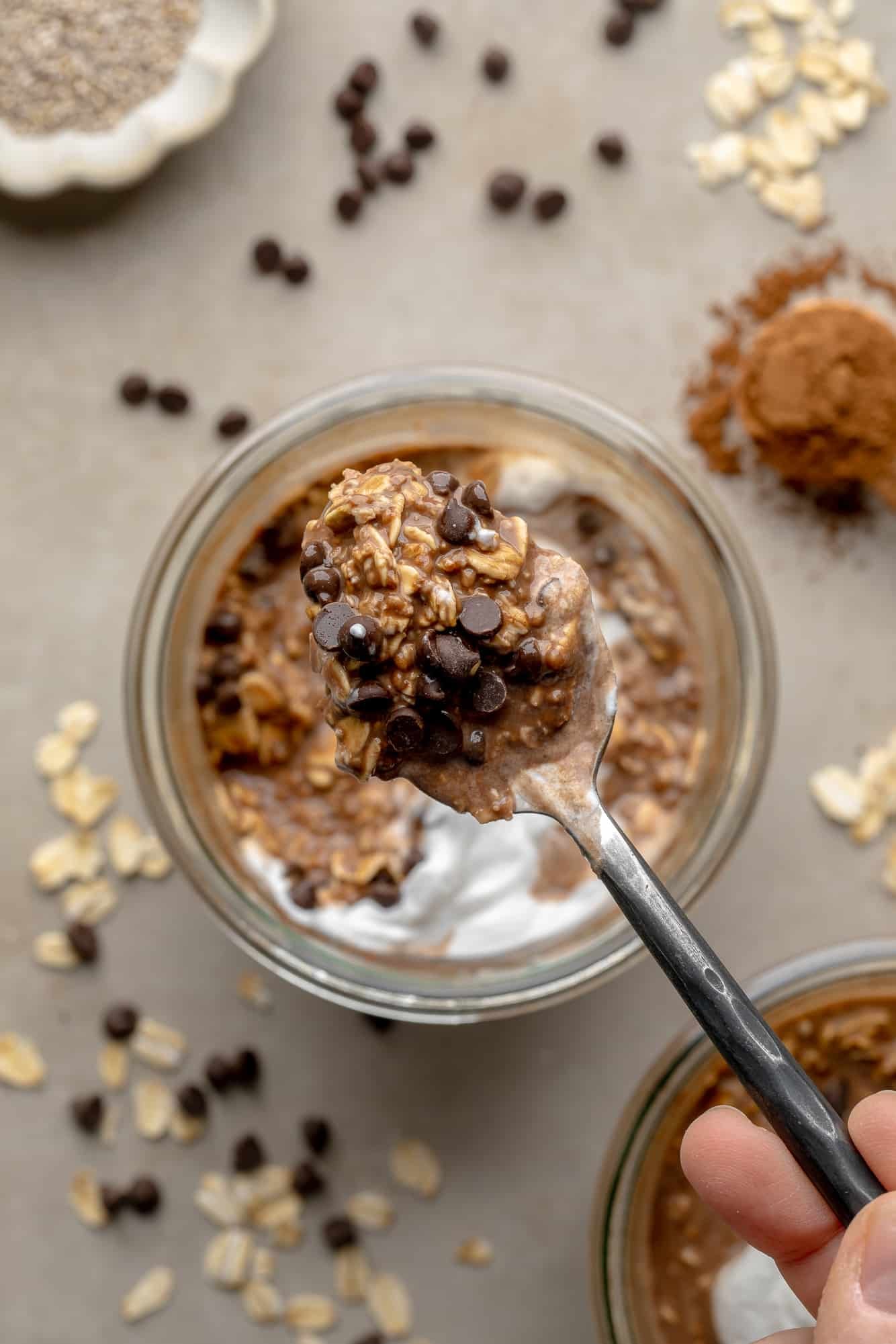 close up on a spoonful of chocolate overnight oats held above a jar of overnight oats.