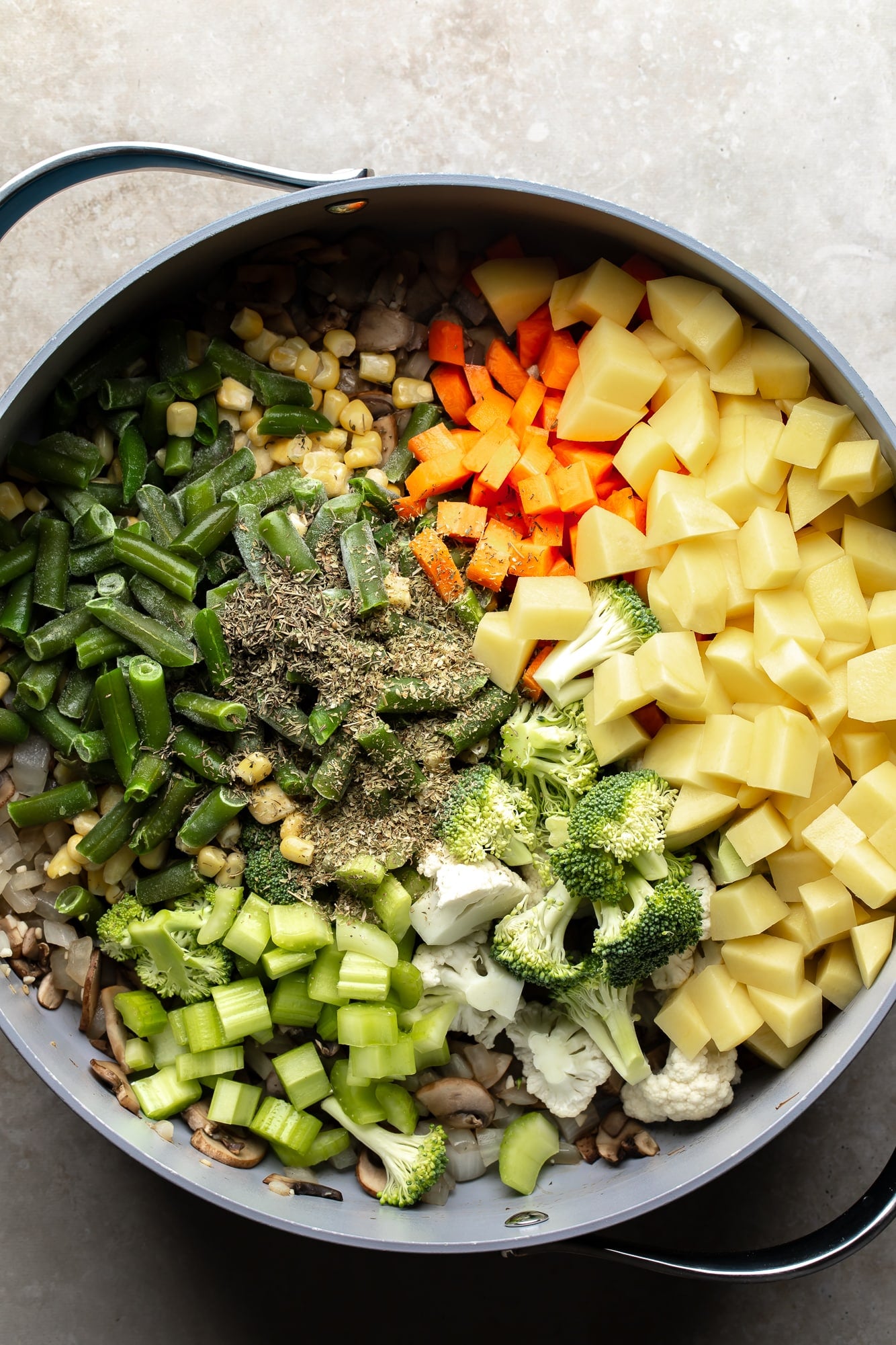 overhead view of the vegetables and seasonings for Creamy Vegetable Soup in a large pot.