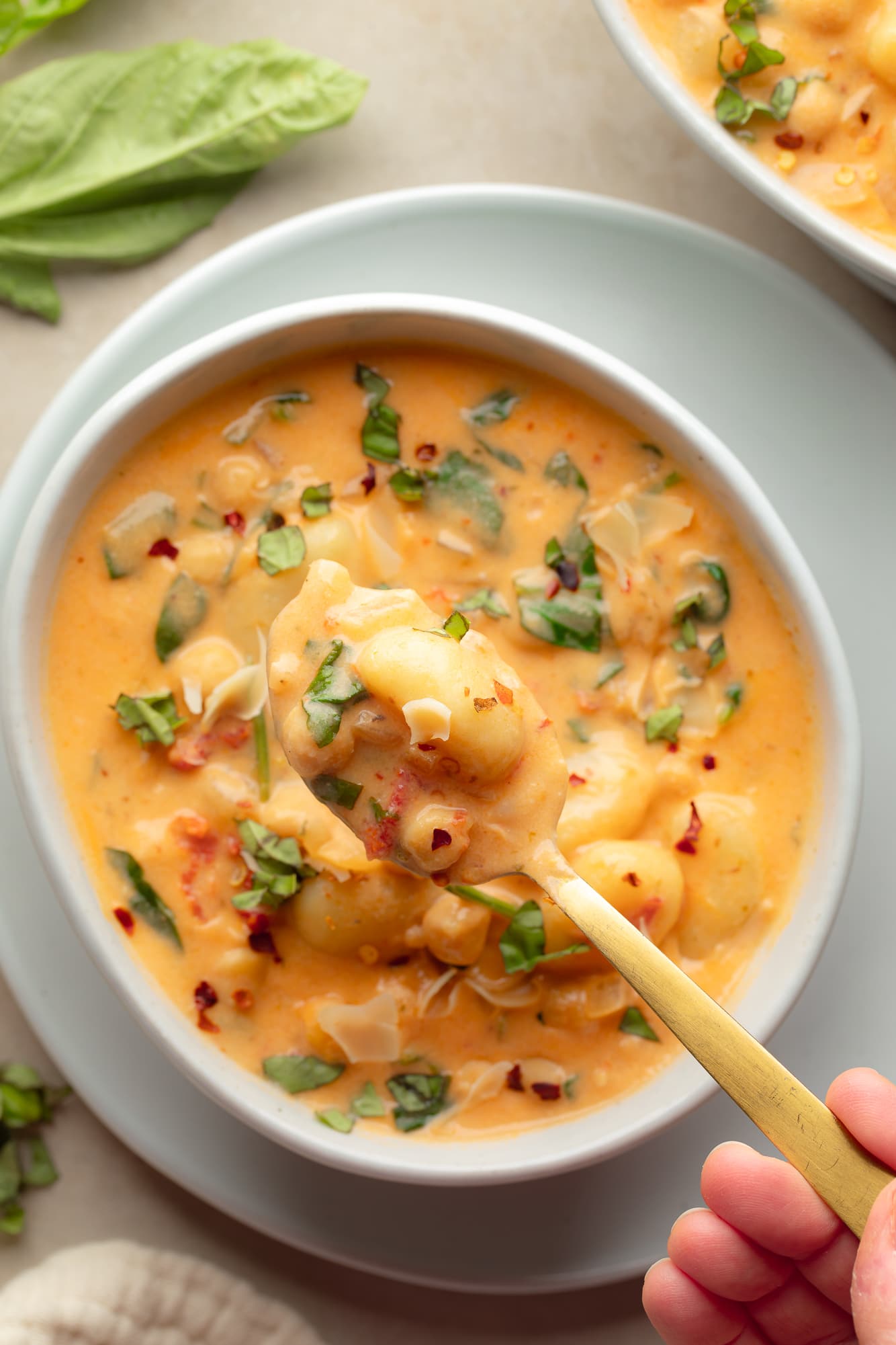 overhead view of a spoonful of vegan marry me gnocchi soup being lifted from a bowl.