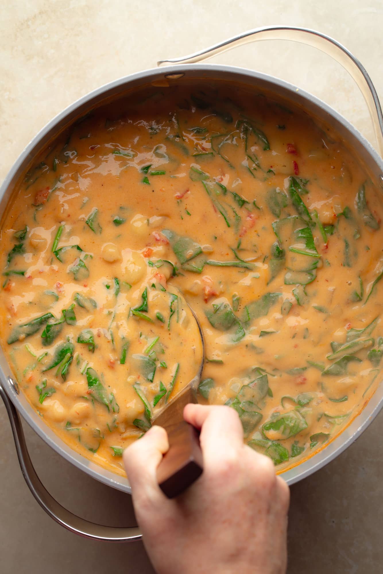 overhead view of a ladle being stirred in a pot of vegan marry me gnocchi soup.