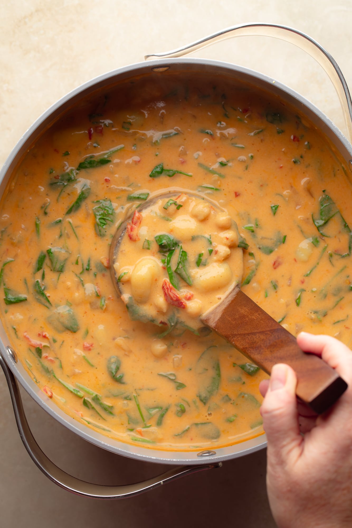 overhead view of a ladle being lifted from a pot of vegan marry me gnocchi soup.