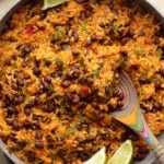 close up on Mexican rice and beans in a pot with lime wedges on the side.
