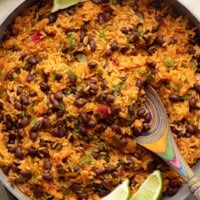 close up on Mexican rice and beans in a pot with lime wedges on the side.