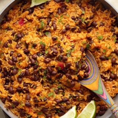 close up on Mexican rice and beans in a pot with lime wedges on the side.