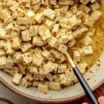 overhead view of tofu feta with a marinade in a large white bowl.