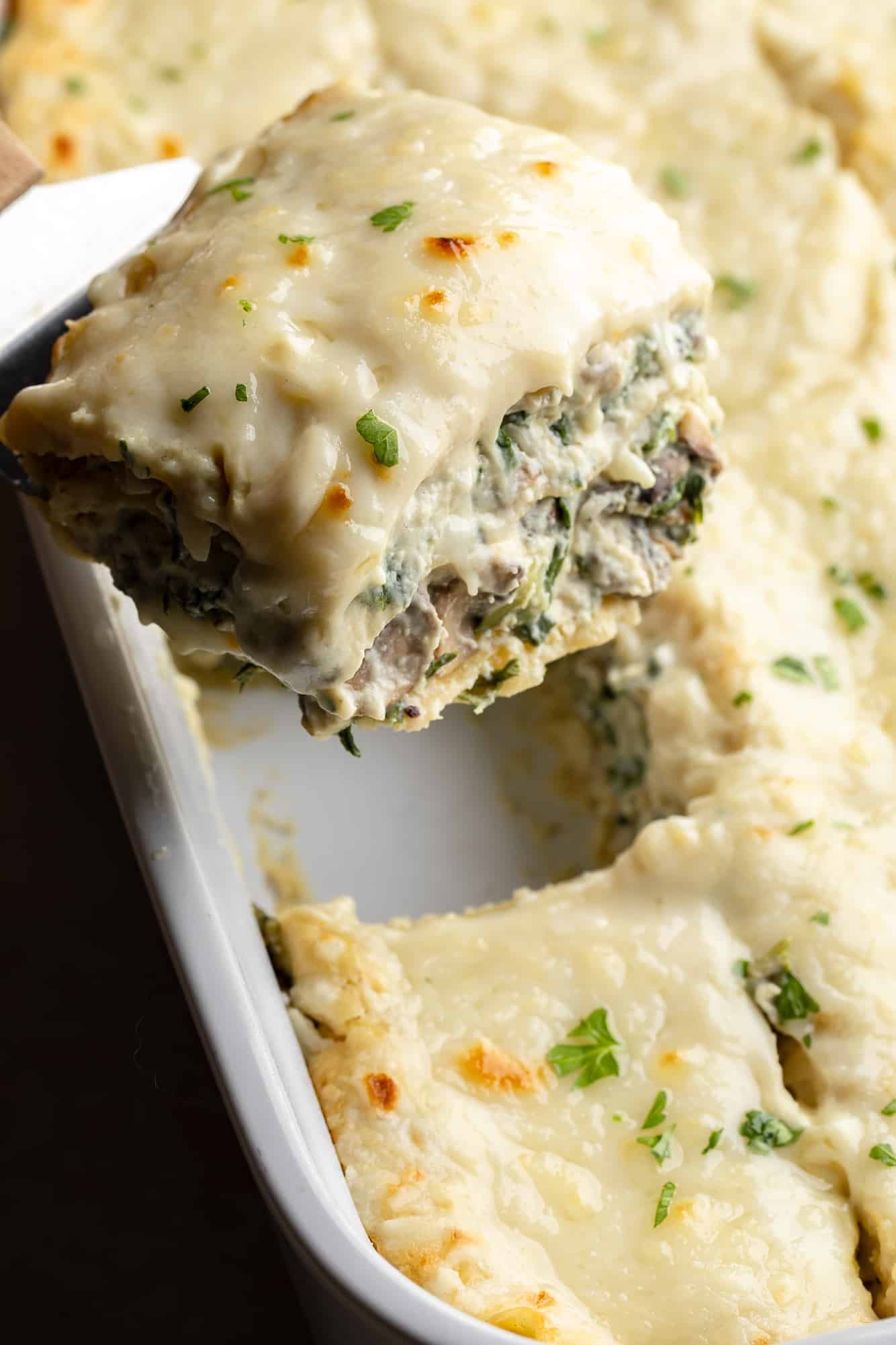close up on a slice of vegan white lasagna being lifted from a casserole dish.