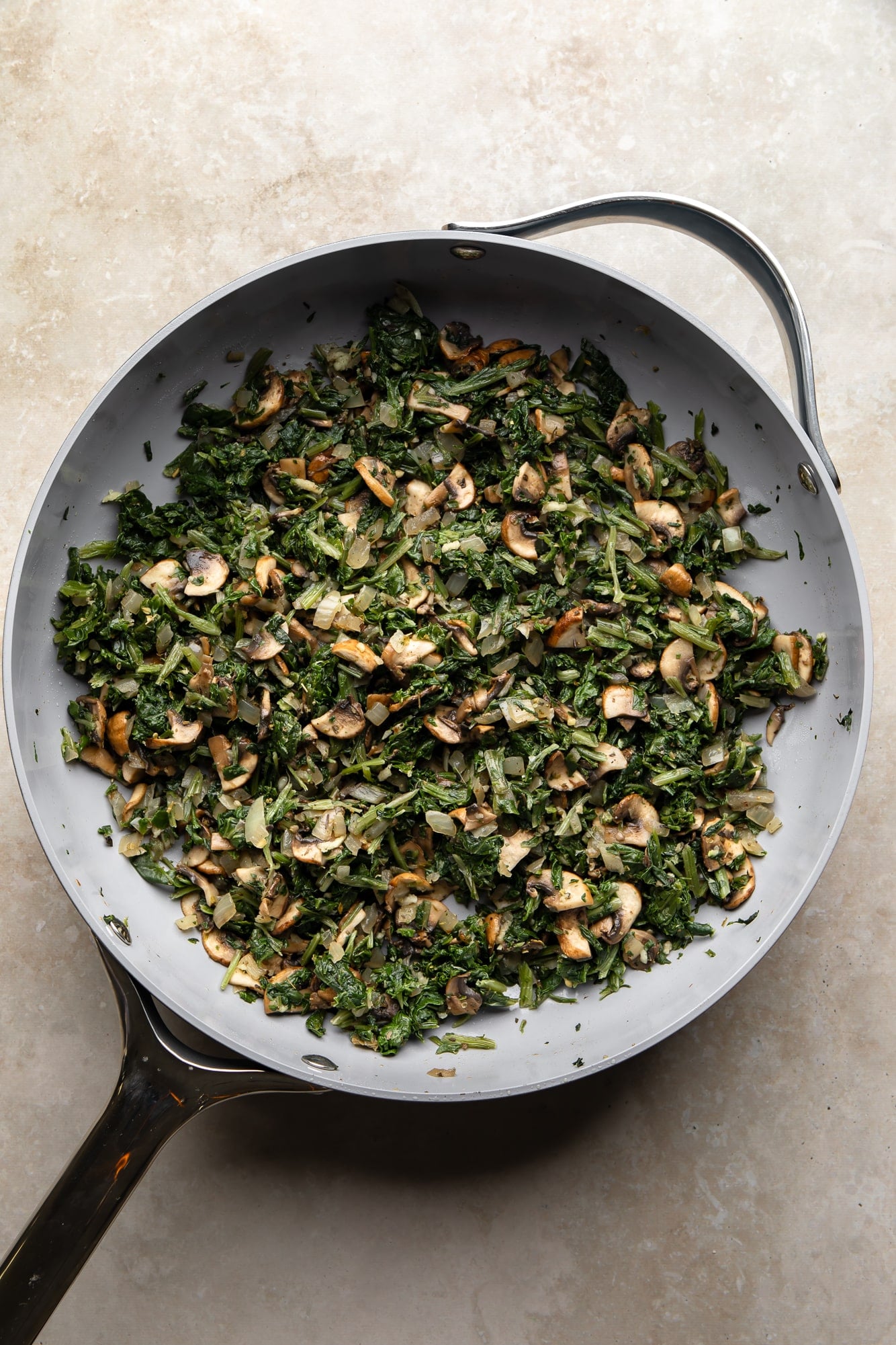 overhead view of cooked mushrooms and spinach for vegan white lasagna in a skillet.