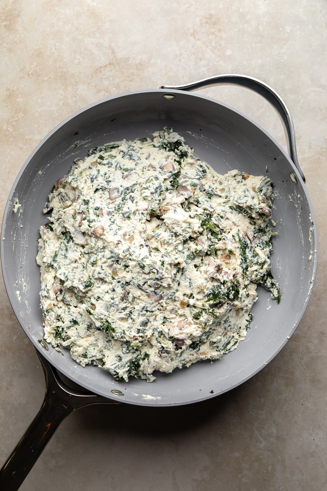 overhead view of mushroom spinach ricotta filling for vegan white lasagna in a skillet.