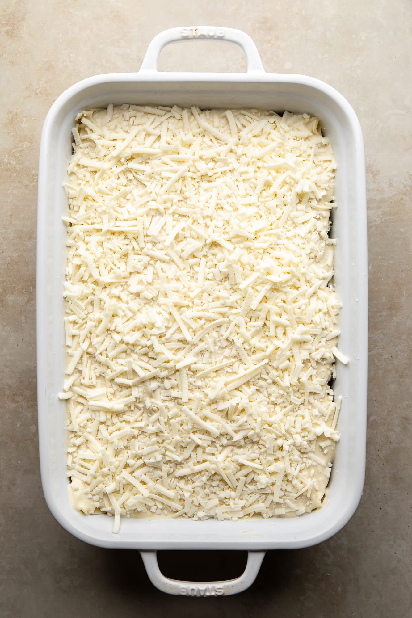 overhead view of a mozzarella-topped vegan white lasagna in a casserole dish.