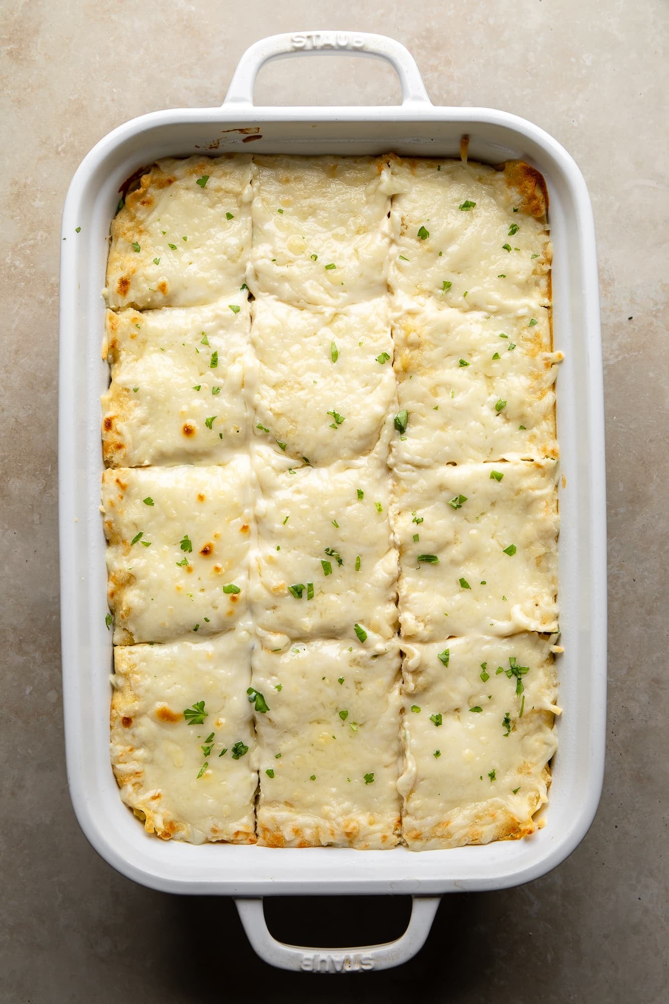 overhead view of a sliced vegan white lasagna in a casserole dish.