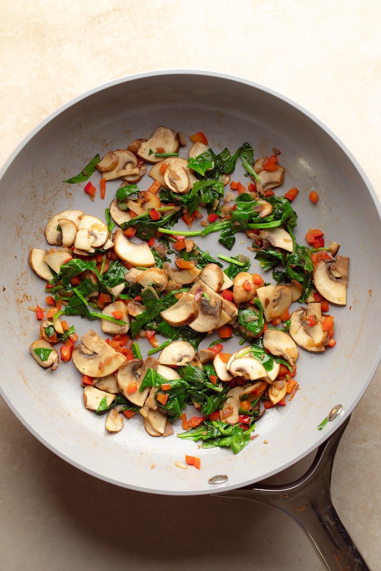 overhead view of the vegetables for a chickpea flour omelette cooking in a skillet.