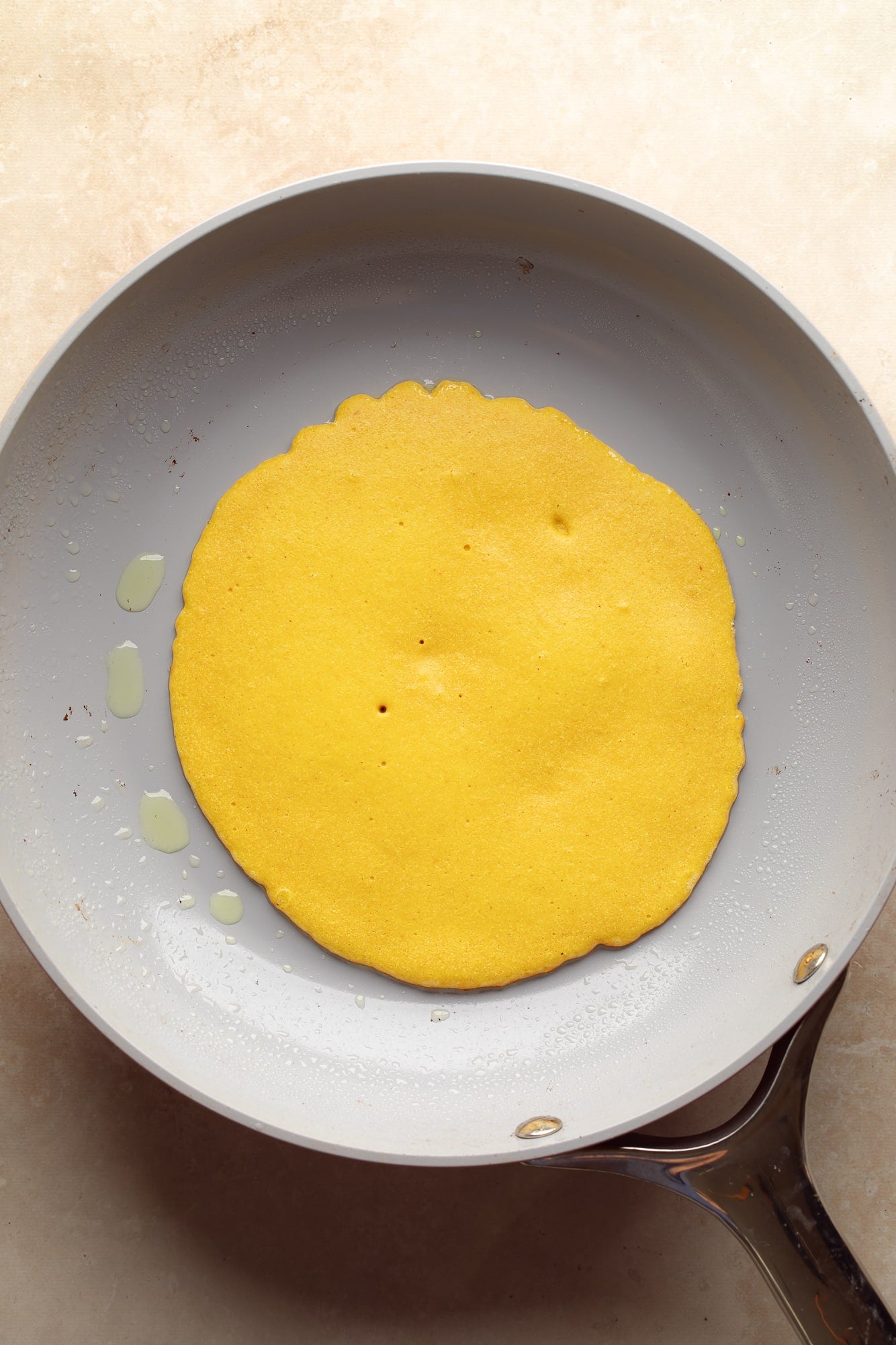 overhead view of a chickpea flour omelette cooking in a skillet.