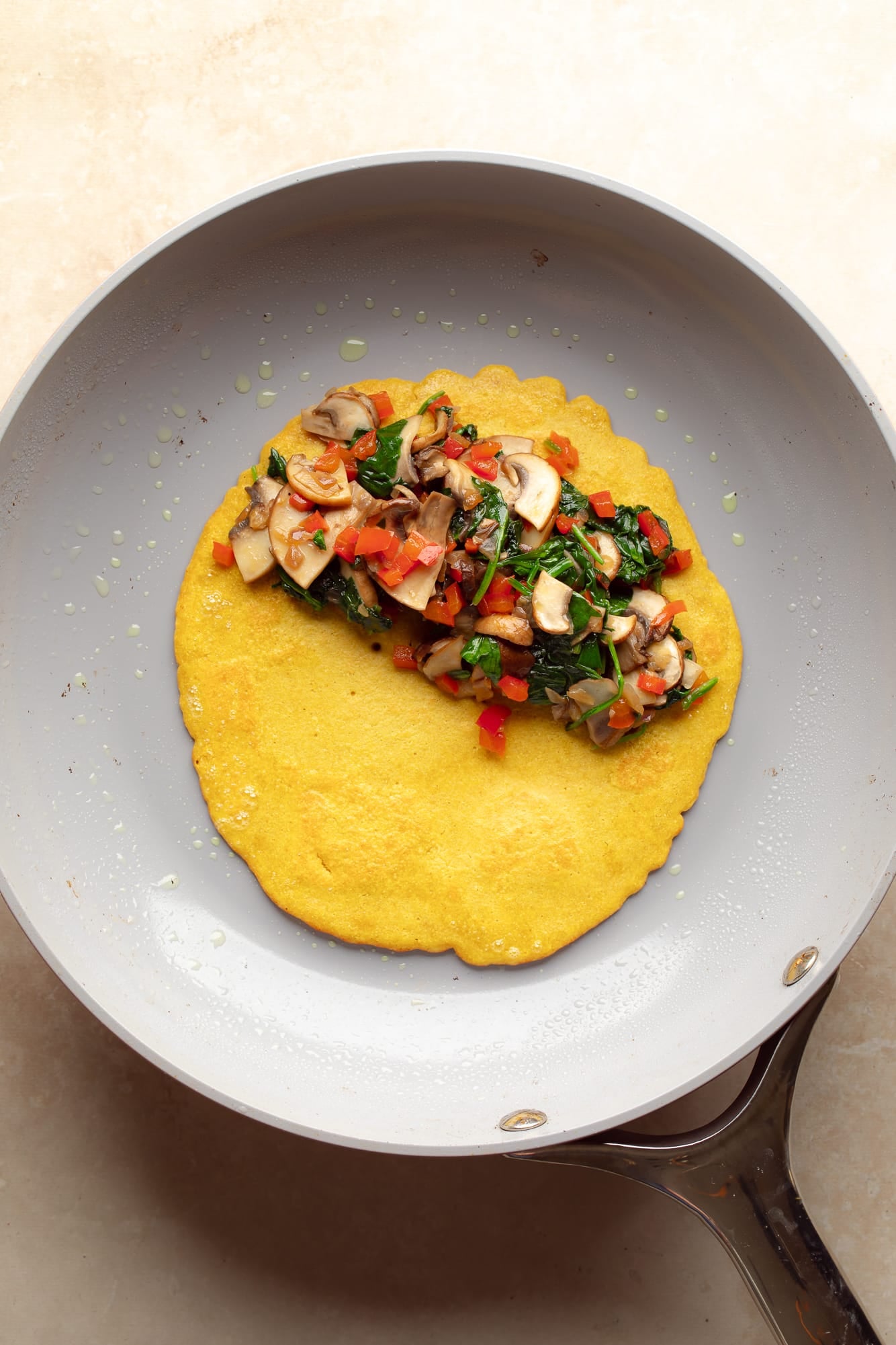 overhead view of a chickpea flour omelette topped with vegetables in a skillet.