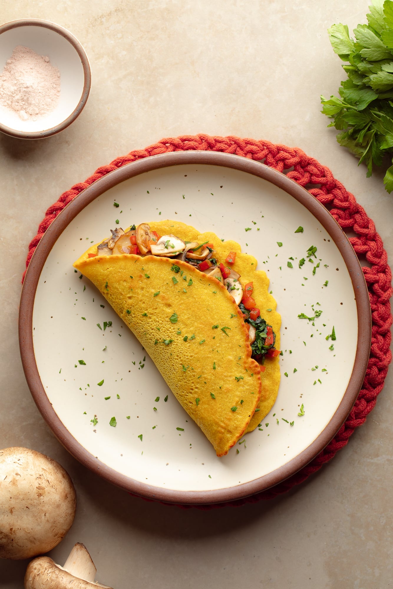 overhead view of a chickpea omelette filled with vegetables on a plate.
