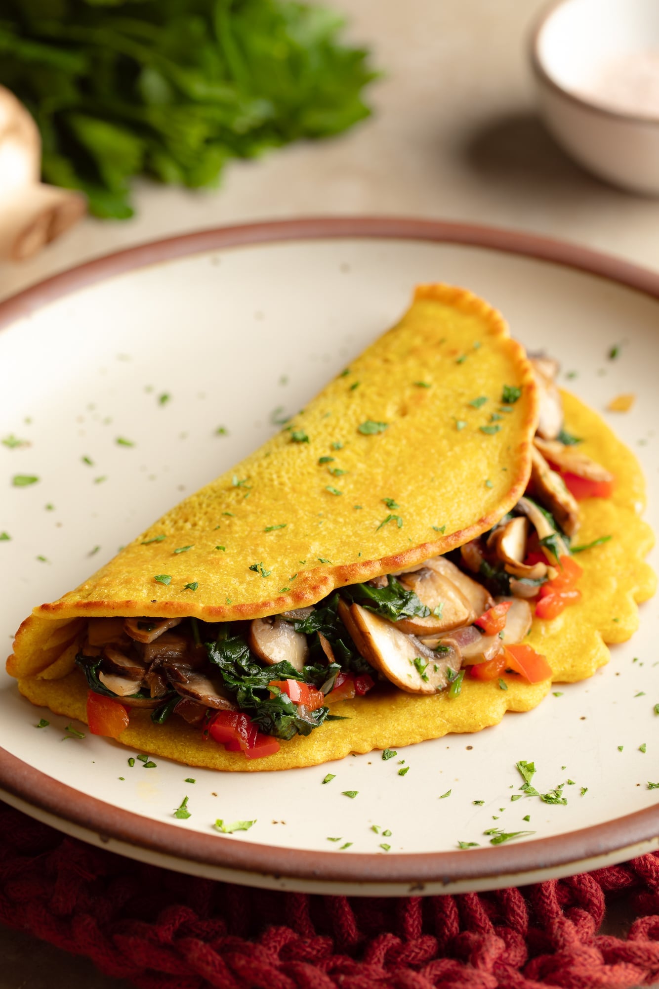 side view of a chickpea omelette filled with vegetables on a plate.
