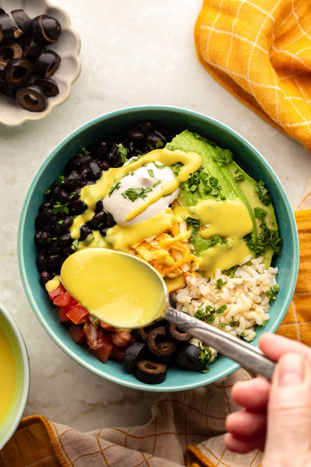 overhead view of a spoon drizzling golden sauce over a comfort rice bowl.