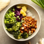 overhead view of a Teriyaki Chickpea Bowl topped with broccoli, edamame, pineapple, and red cabbage.