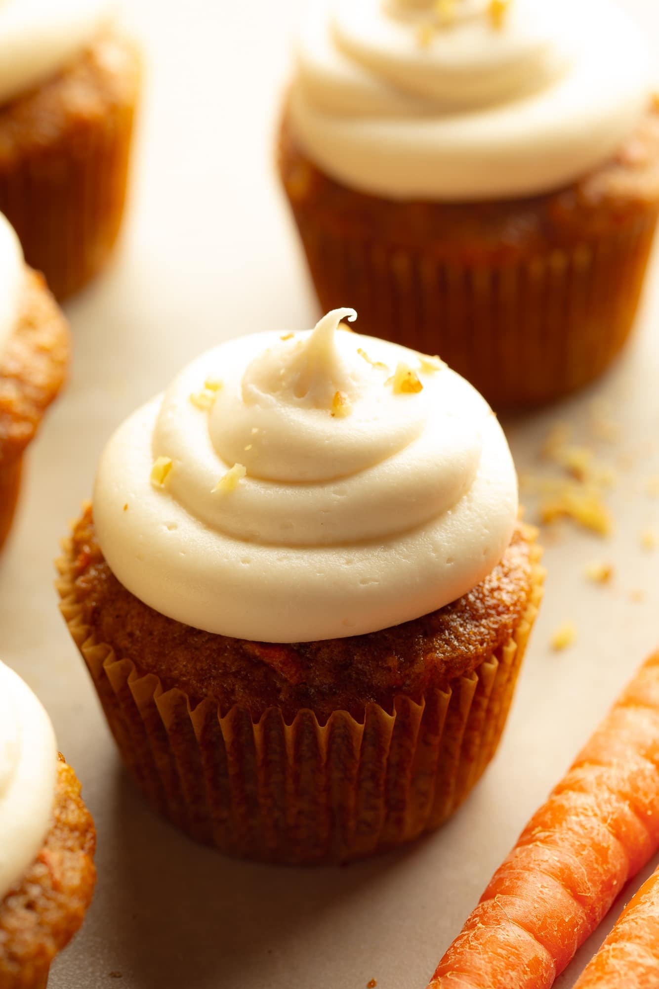 side view of a vegan carrot cake cupcake topped with vegan cream cheese icing.
