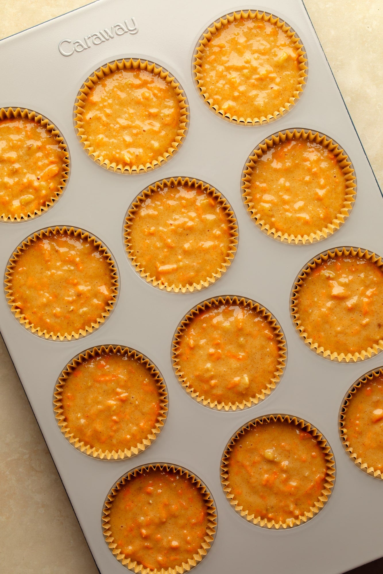 overhead view of unbaked vegan carrot cake cupcakes in a muffin tin.