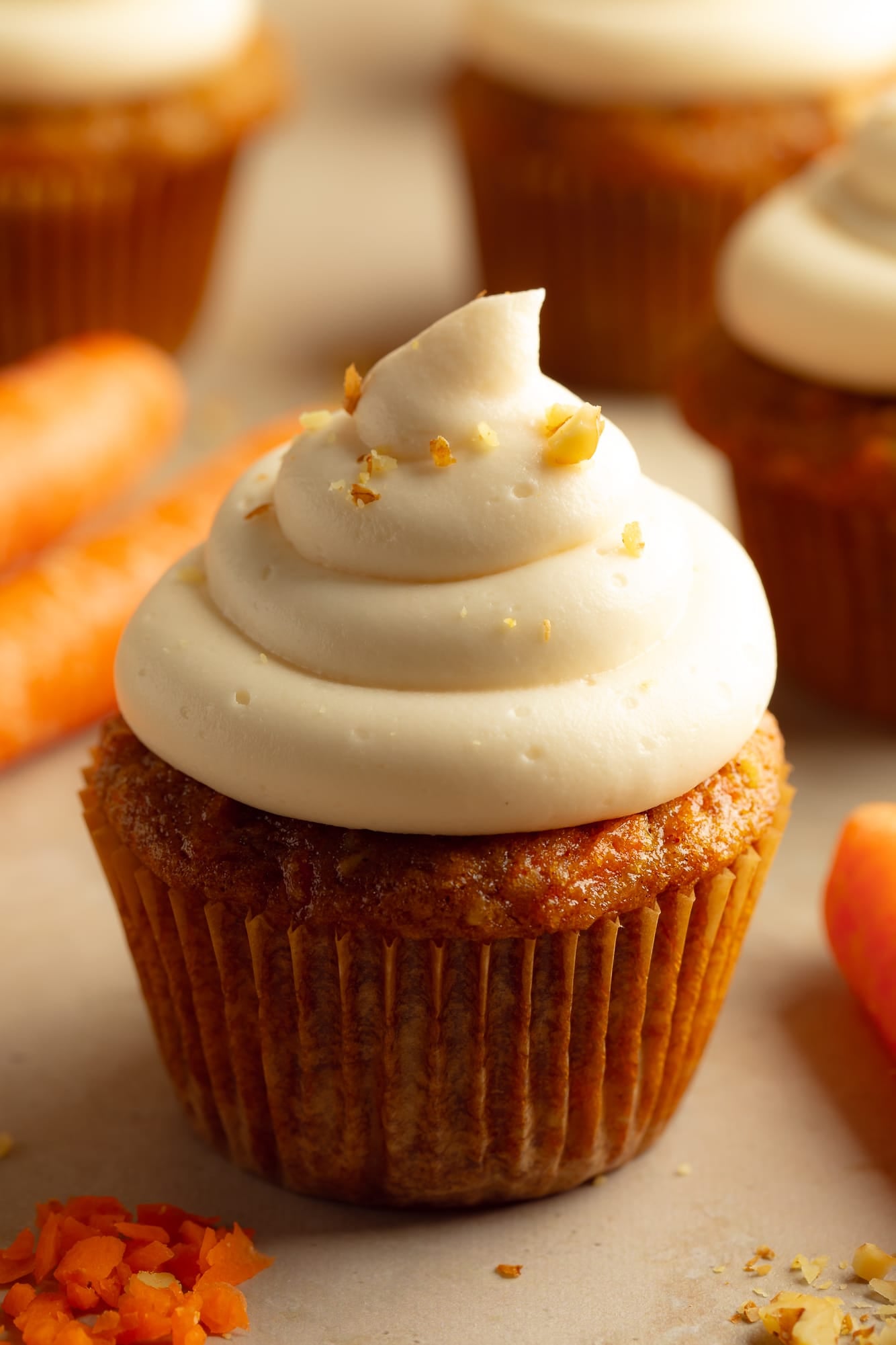 side view of a vegan carrot cake cupcake topped with vegan cream cheese frosting.