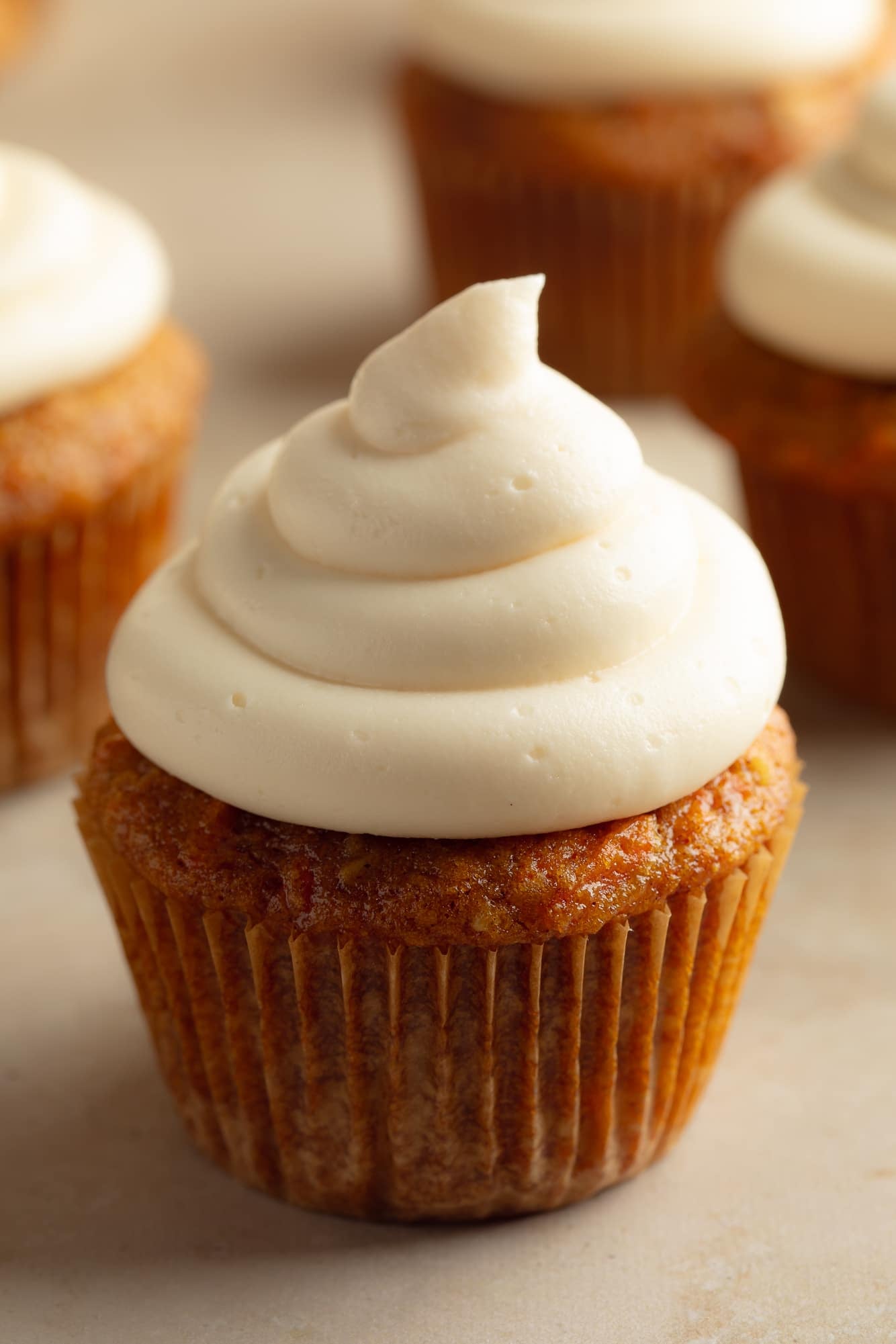 close up on a carrot cake cupcake topped with piped vegan cream cheese frosting.