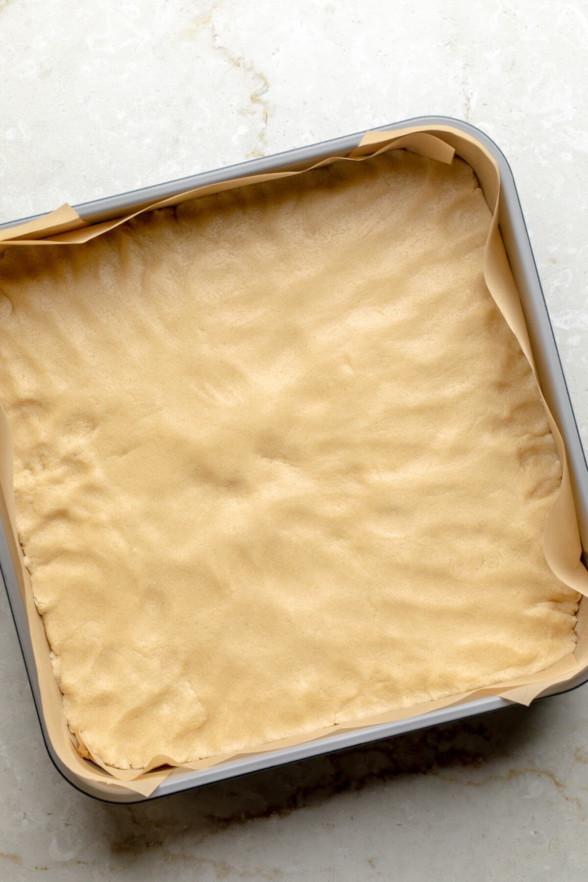 overhead view of a raw shortbread cookie crust in a baking pan.