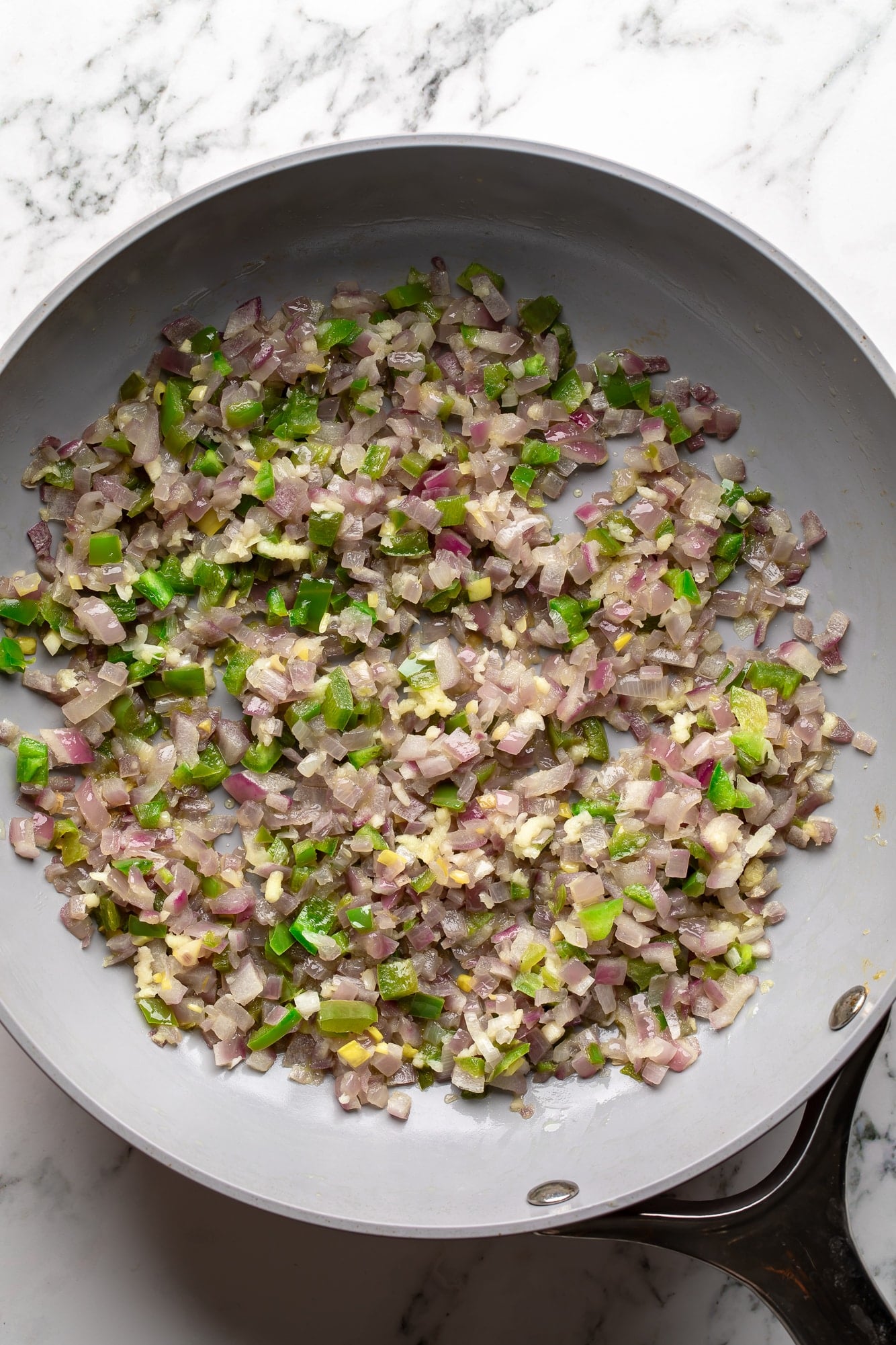 overhead view of a skillet filled with cooked onions, jalapenos, and garlic.
