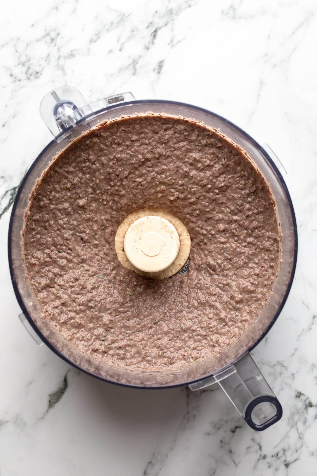overhead view of a smooth, blended black bean dip in a food processor.