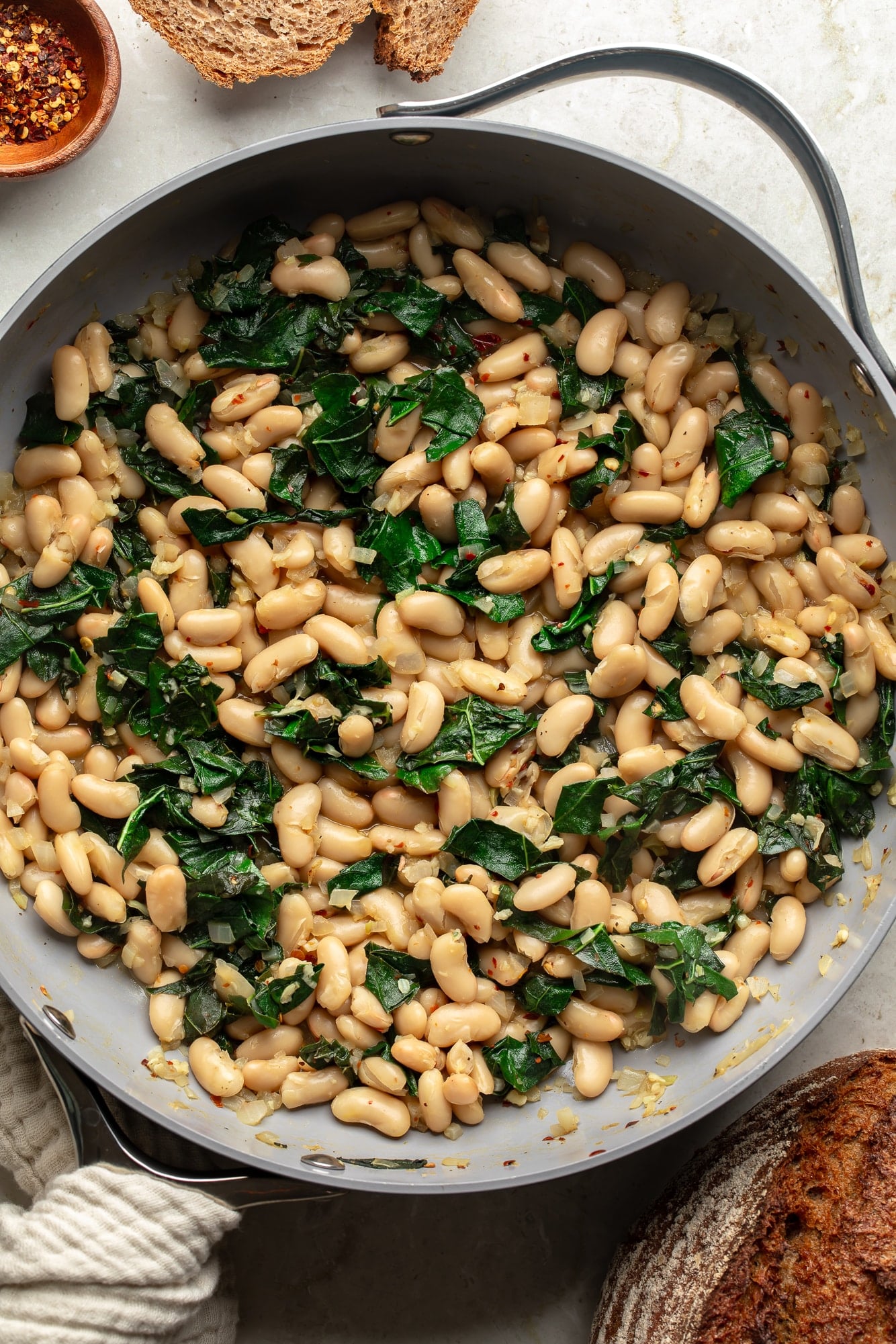 overhead view of a skillet full of braised white beans and kale.