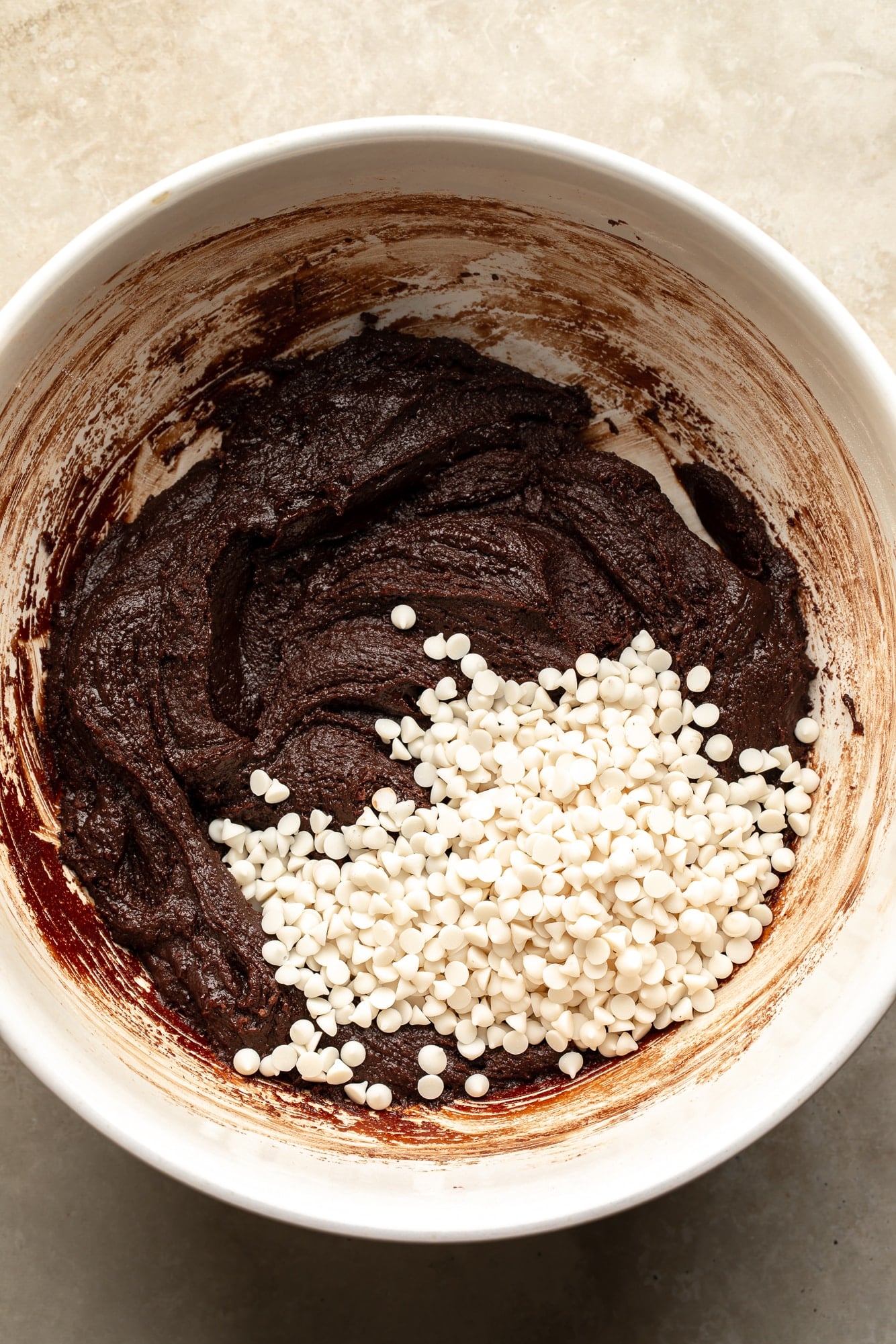 overhead view of vegan brownie batter with white chocolate chips on top in a large bowl.