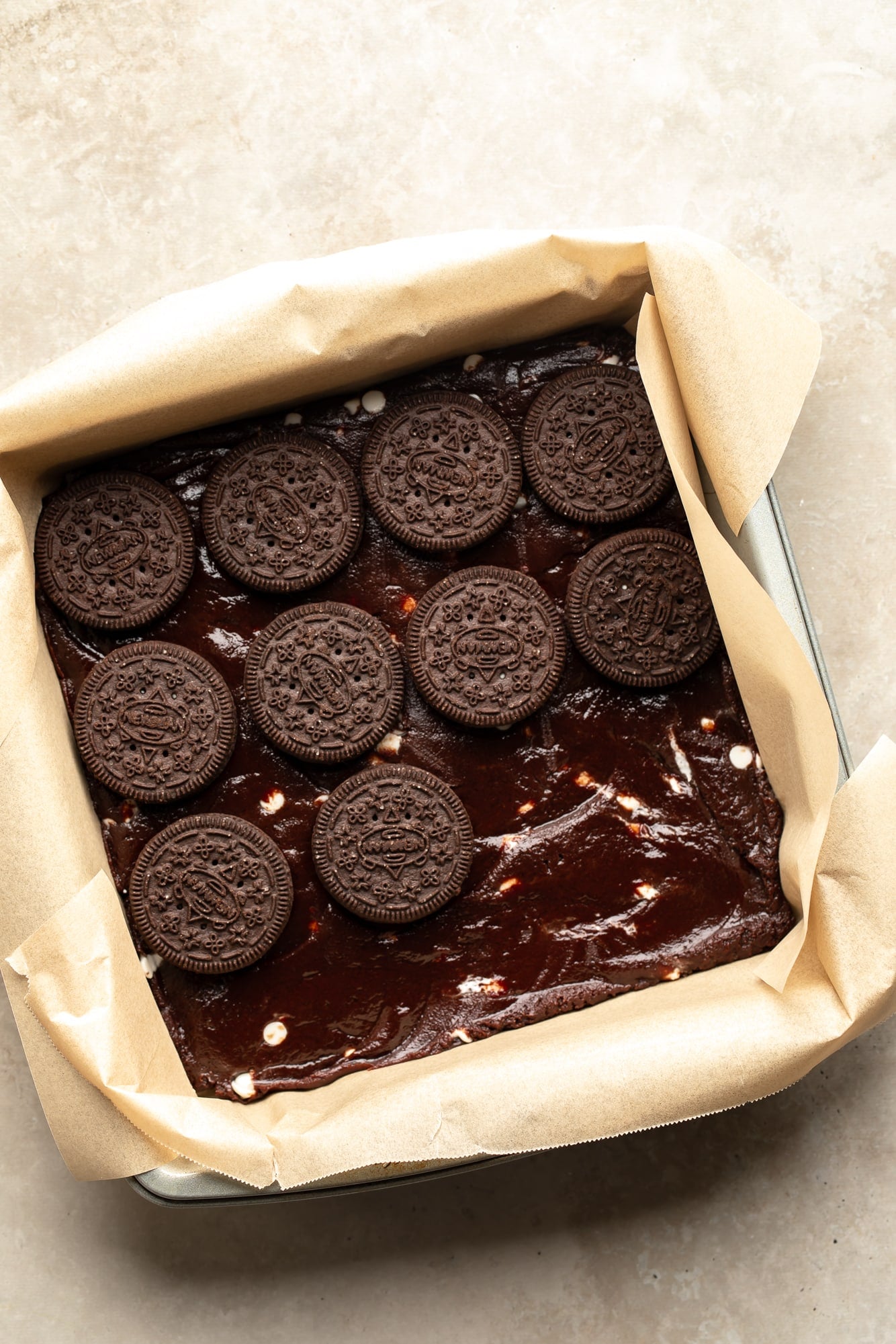 overhead view of Oreo cookies being layered on top of vegan brownie batter in a baking pan.